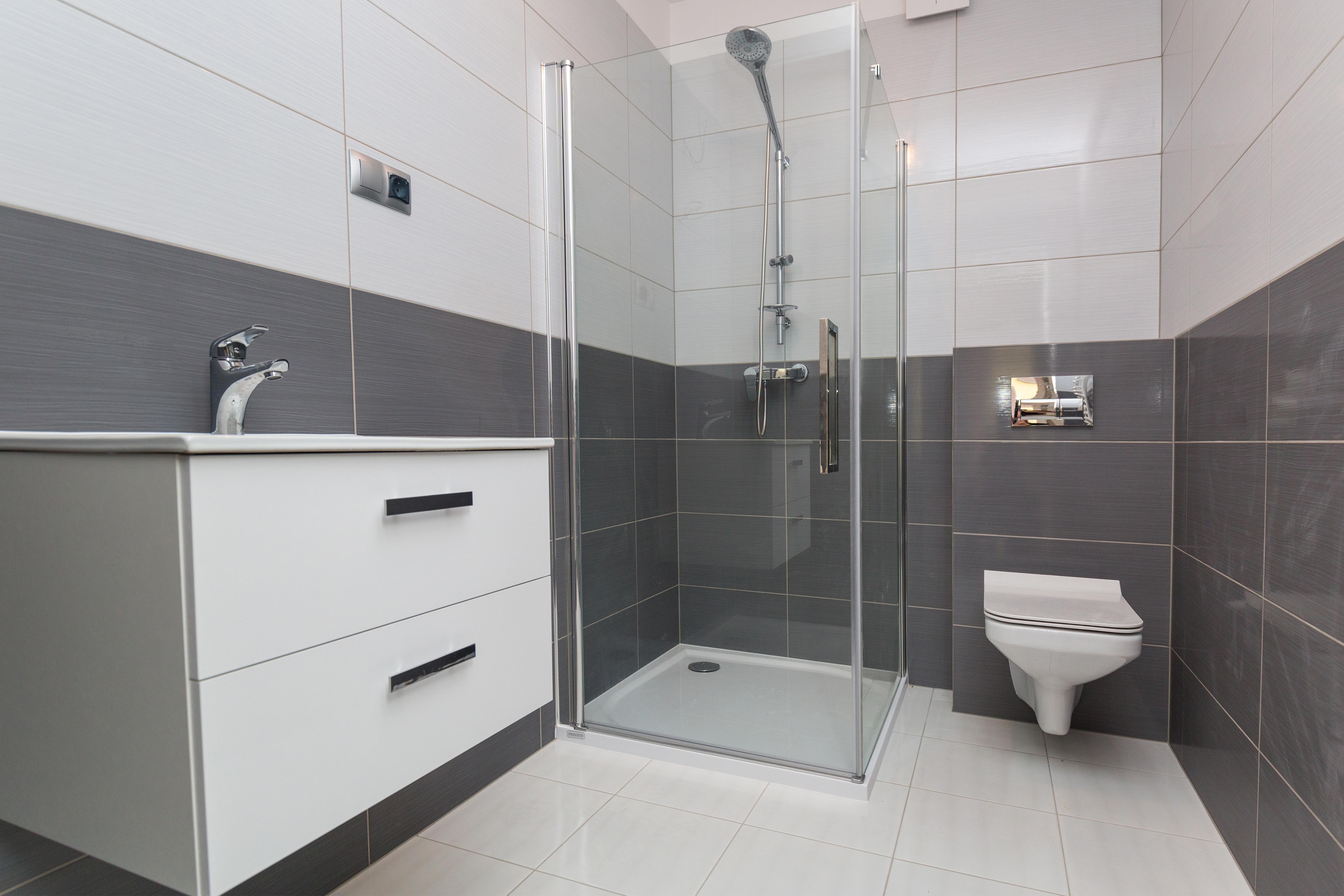 Modernes neu gebautes Badezimmer mit Eck-Glasdusche, Wand-WC und weißem Waschtisch