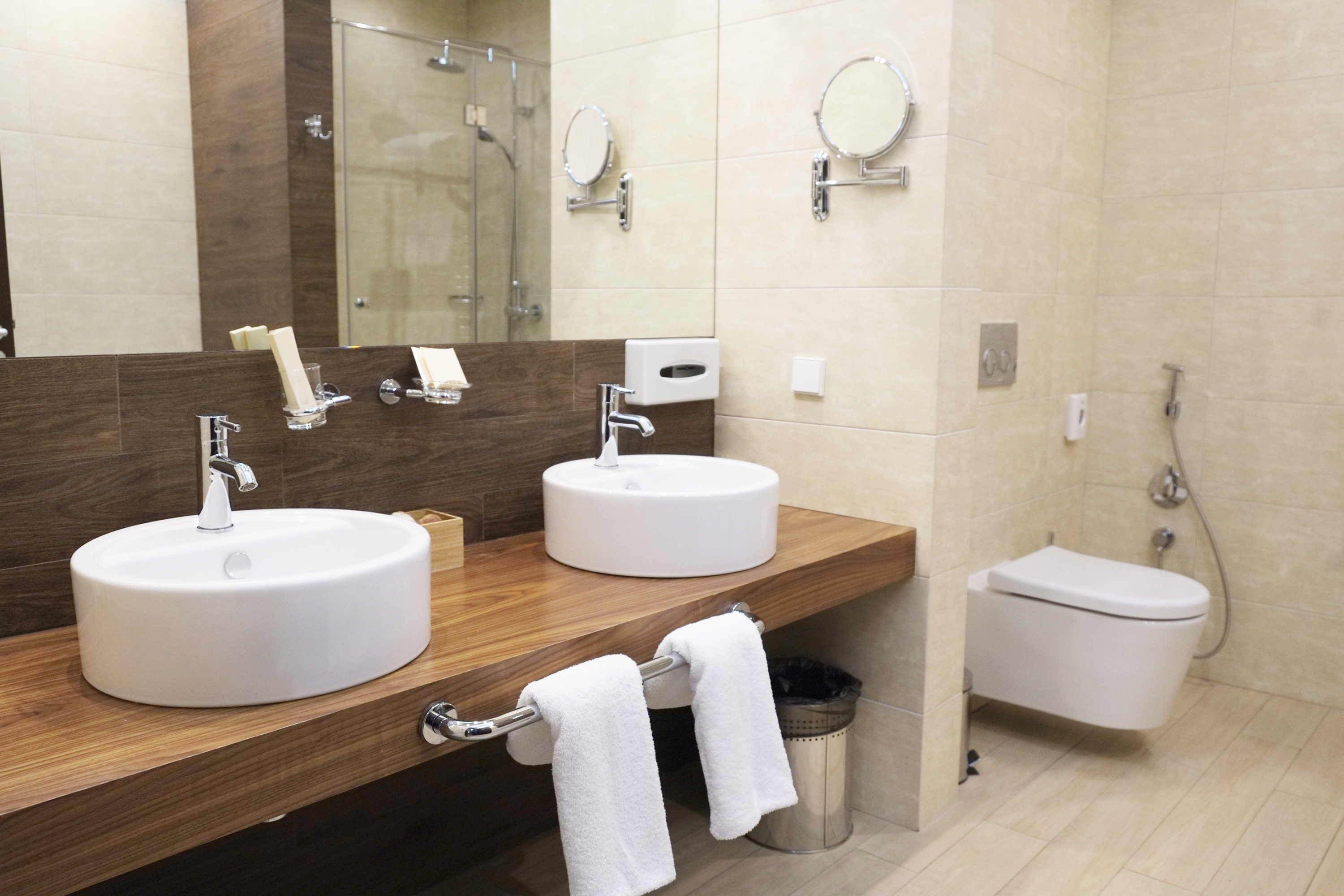 Hochwertiges Badezimmer mit zwei runden Aufsatzwaschbecken auf Holzplatte und Wand-WC