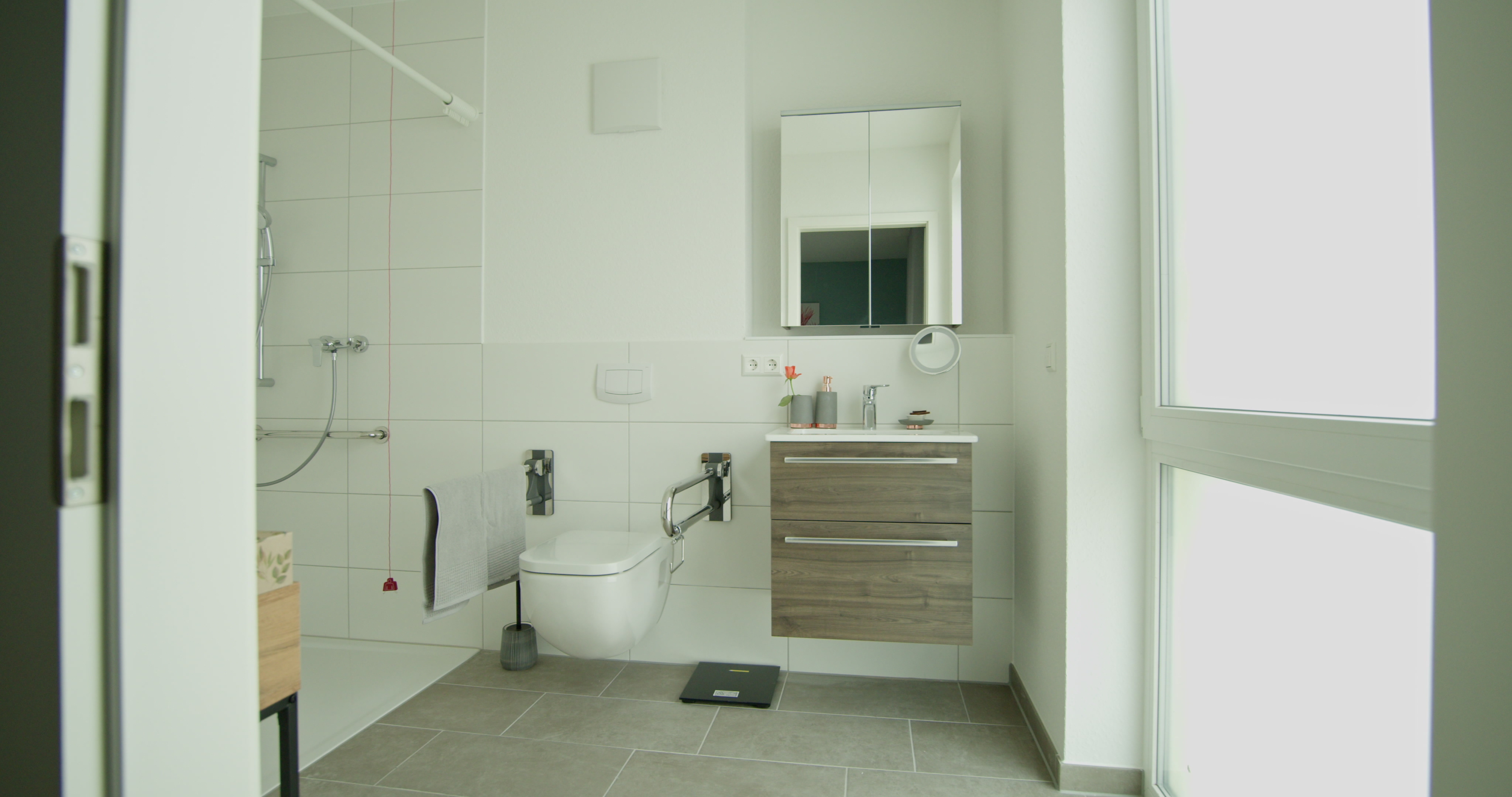 Helles barrierefreies Badezimmer mit rollstuhlgerechter Dusche und moderner Ausstattung